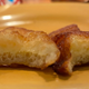 Two bitten-into French toast sticks sit next to each other on a plate.